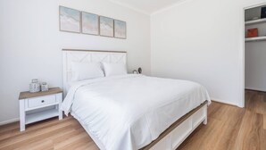 A bedroom with a bed, a nightstand, a dresser, and a closet. - Foreshore Haven Poolside Comfort near Rye Beach (Rye)