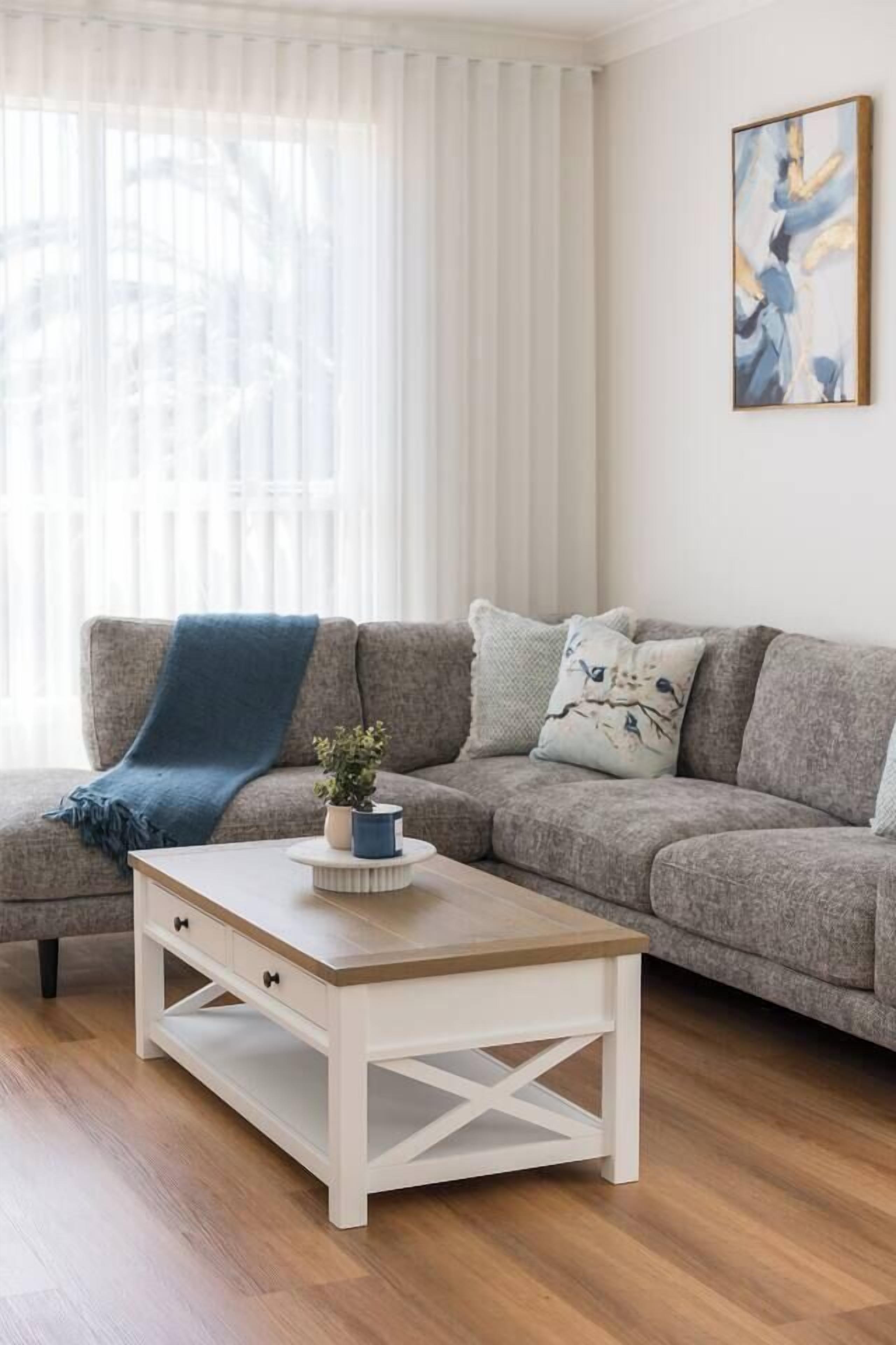 A living room with a grey sofa, a white coffee table, and a painting on the wall.