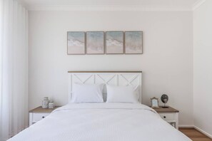 A bedroom with a bed, two bedside tables, a nightstand, and three wall-mounted paintings. - Foreshore Haven Poolside Comfort near Rye Beach (Rye)