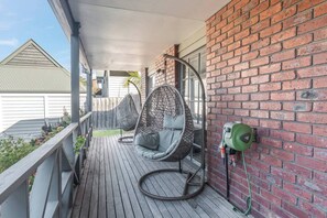 Eine Holzterrasse mit einer Hängematte und einer Wasserpumpe.