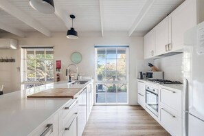 Una cocina moderna con armarios blancos, una isla grande y vistas a través de las ventanas.