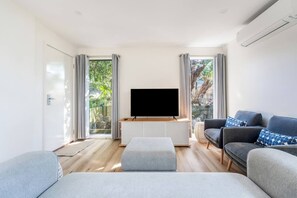 A modern living room with a flat-screen TV, grey sofas, and a wooden floor. - The Shack Your Ultimate Family Escape by the Sea (Rye)