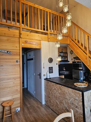 A wooden interior with a kitchen area, a wooden staircase, and a sign indicating 'LA DRAILLE'. - Panoramic View of the Ecrins - Balcony at 1,700 - Sleeps 4–6 (Puy Saint Vincent)