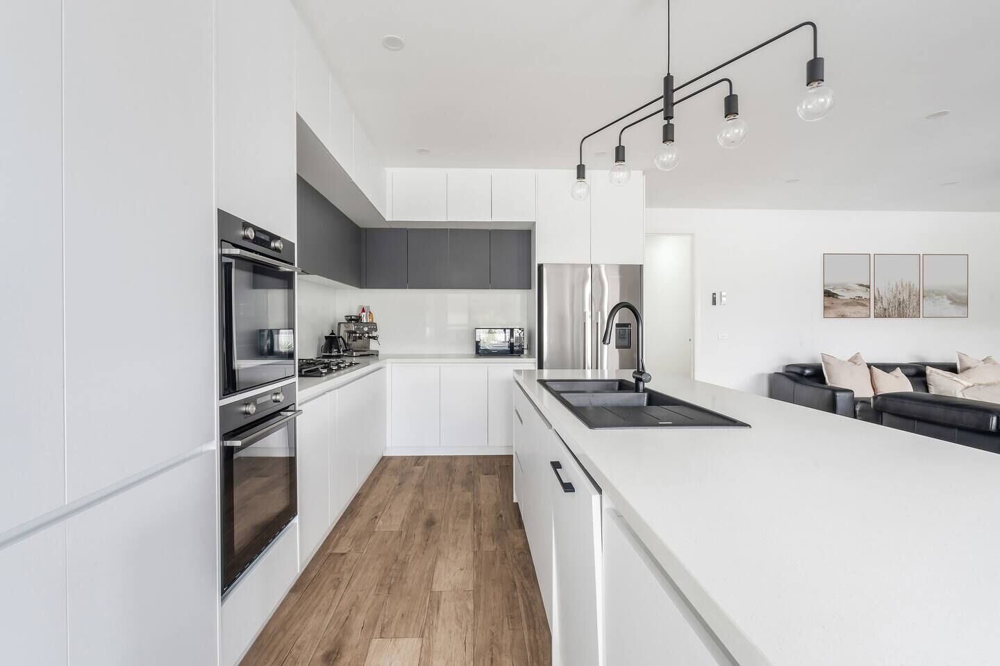 A modern kitchen with white cabinetry, a stainless steel refrigerator, and a black countertop.