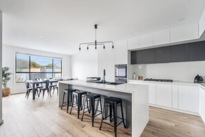 Uma cozinha moderna com uma ilha central, banquetas de bar e uma área de refeições com vista.