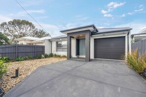 Ein modernes, zweistöckiges Haus mit Garage, Auffahrt und umzäunter Garten.