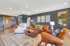 Ein Wohnzimmer mit einem weißen Sofa, einem braunen Ledersofa, einem Couchtisch und einem gemusterten Teppich.