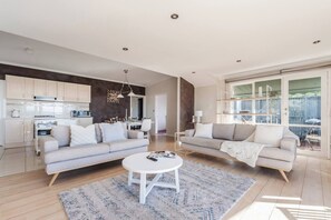 Ein modernes Wohnzimmer mit einer Couch, einem Couchtisch und einem Essbereich mit Tisch und Stühlen.