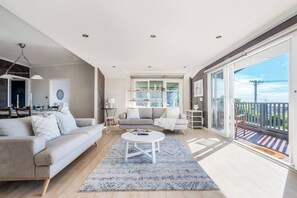 Ein geräumiges Wohnzimmer mit einer Couch, einem Couchtisch und einem Balkon mit Blick.