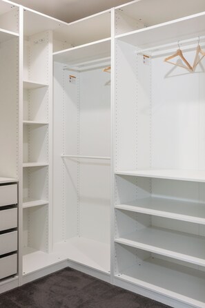 A walk-in closet with open shelving, a hanging rod, and a built-in drawer unit. - Reverie Poolside Haven near Beaches and Hot Springs (Rye)