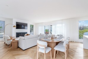 Un salon moderne doté d’un téléviseur à écran plat, d’une cheminée et d’un coin repas avec une table ronde et des chaises.