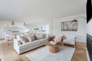 A modern living room with a sofa, chairs, a coffee table, and a painting on the wall. - Reverie Poolside Haven near Beaches and Hot Springs (Rye)