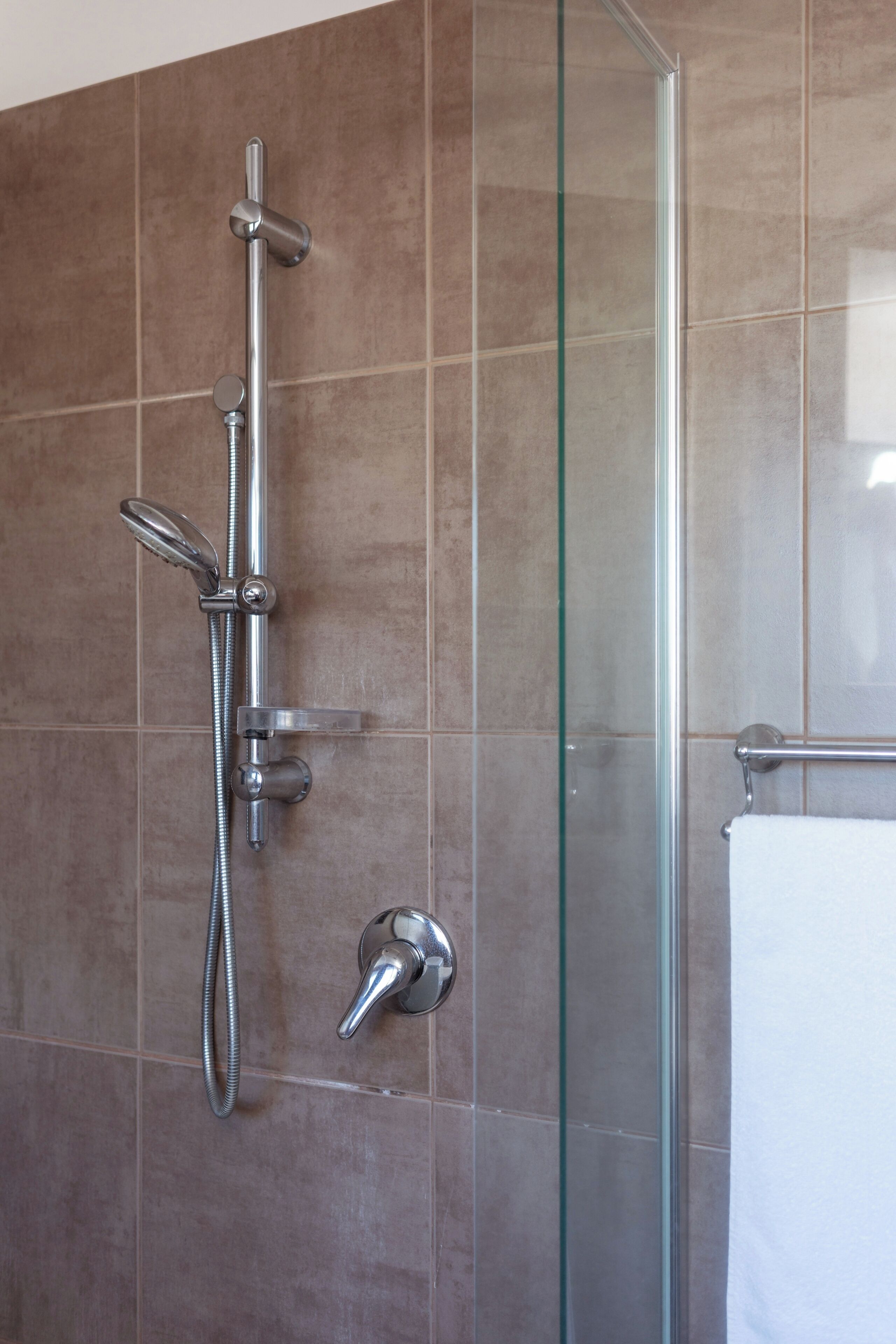 Une salle de bain dotée d’une douche à parois de verre, d’un pommeau de douche à main, d’un robinet mural et d’un porte-serviettes.