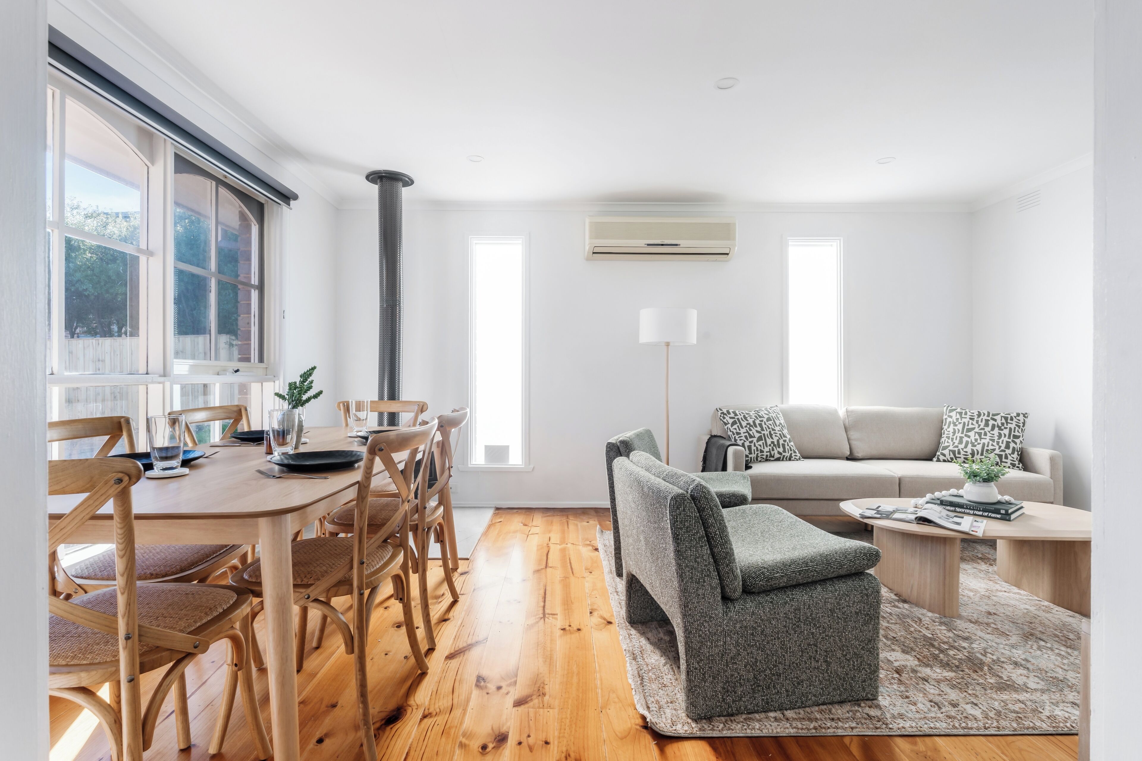 A modern living room with a dining area, featuring wooden furniture, a sofa, and a coffee table.