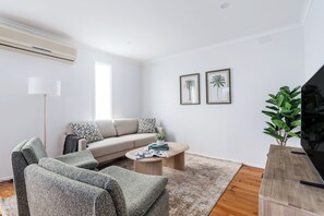 A modern living room with a sofa, armchairs, a coffee table, and a TV stand.