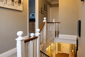 Eine Treppe mit weißen Balustraden und Holzhandläufen, die zu einer oberen Etage führt.