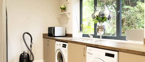 A compact laundry room with a washing machine, dryer, and a vacuum cleaner.