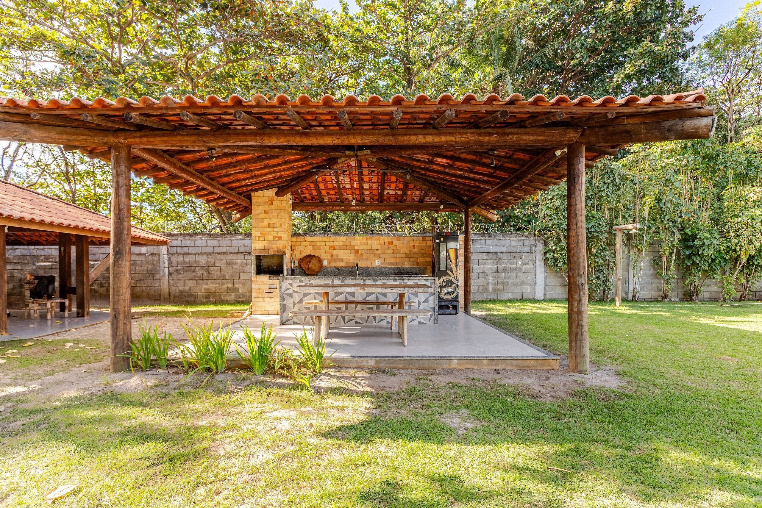 Un área de barbacoa al aire libre con horno de ladrillo, una mesa de madera y un espacio de estar techado.
