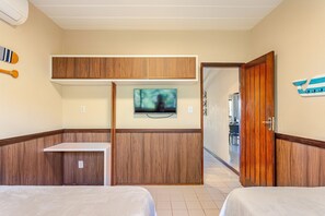 Habitació d'hotel amb un llit, una televisió penjada a un panell de fusta i una porta de fusta.