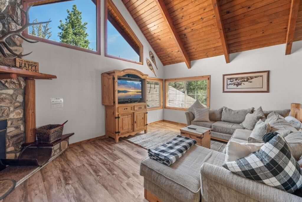 Una sala de estar acogedora con chimenea, muebles de madera y un ventanal con vistas al exterior.