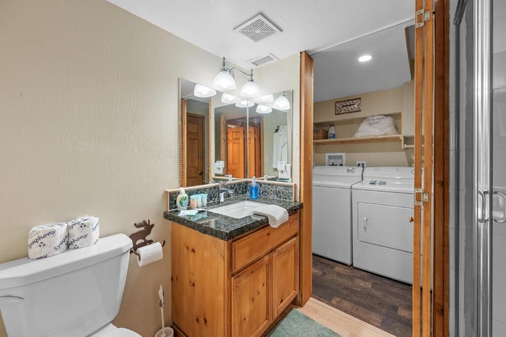 Een badkamer met toilet, wastafel, spiegel en houten kastjes.