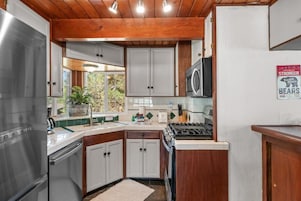 A kitchen with wooden cabinets, a stainless steel refrigerator, a microwave, and a stove.