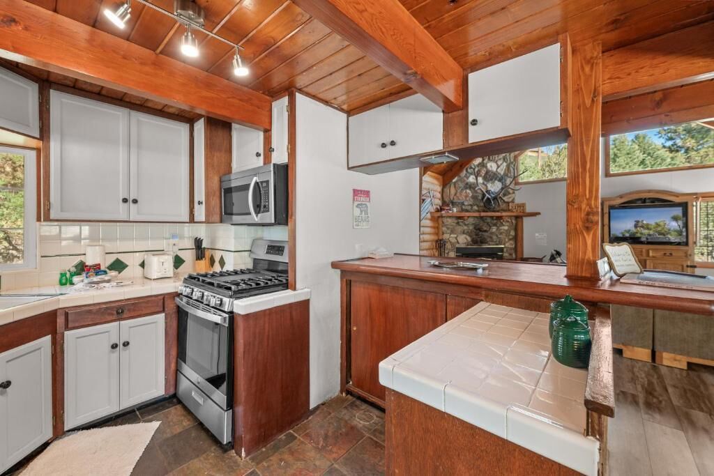 Una cocina con armarios de madera, microondas, estufa y salpicadero de piedra.