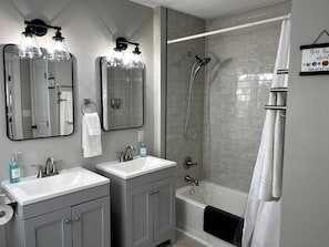 Un baño con dos lavamanos, una bañera y una ducha.