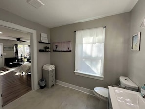 Baño con inodoro, lavamanos y ventana con cortinas.