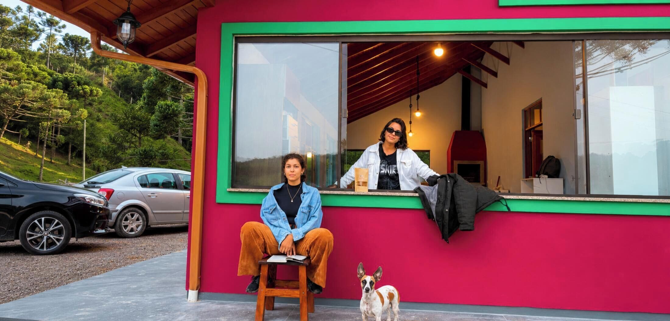 Un bâtiment rouge avec une grande fenêtre, un banc en bois et un chien.