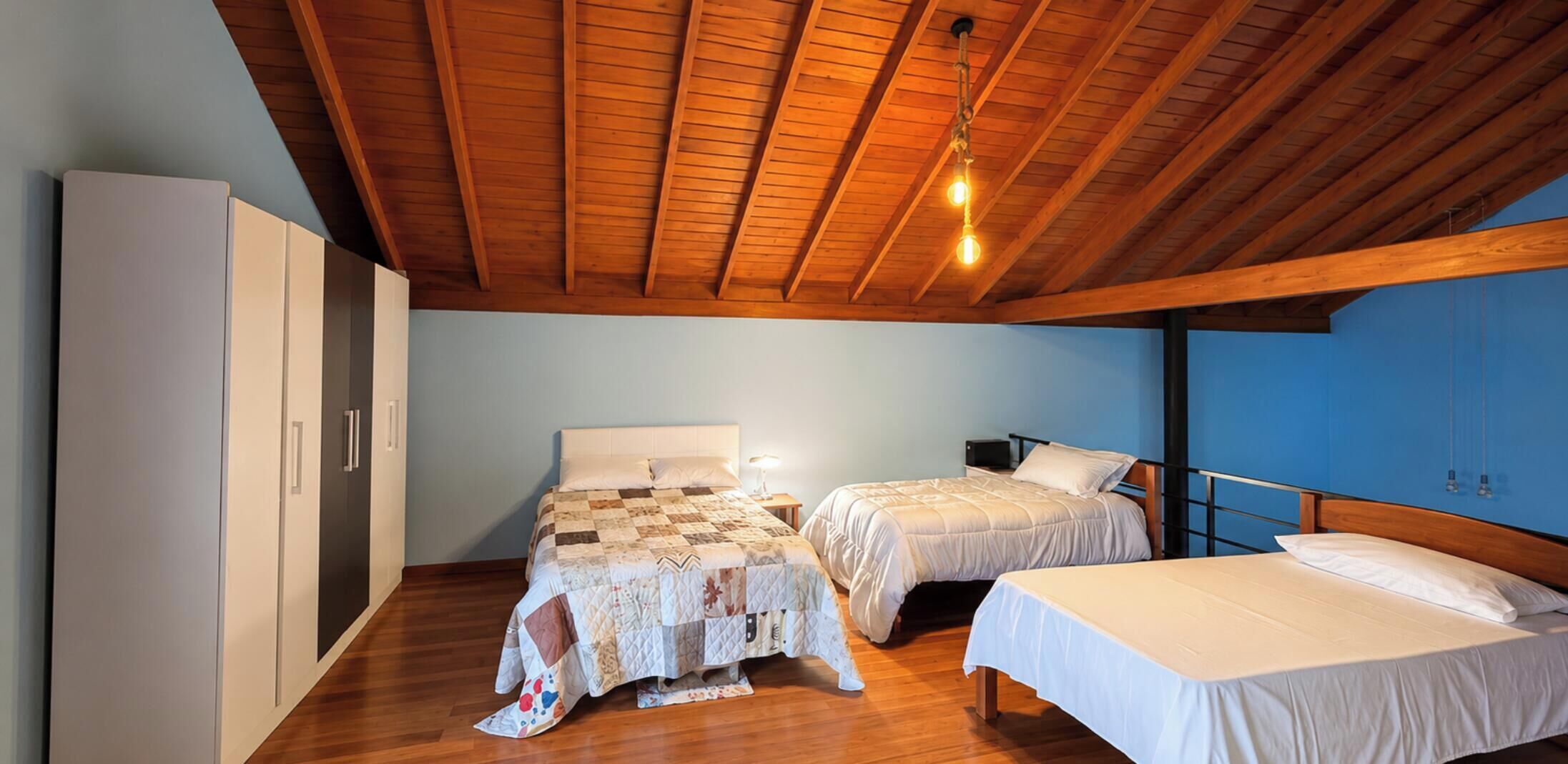 Une chambre avec deux lits, une armoire et un plafond en bois.