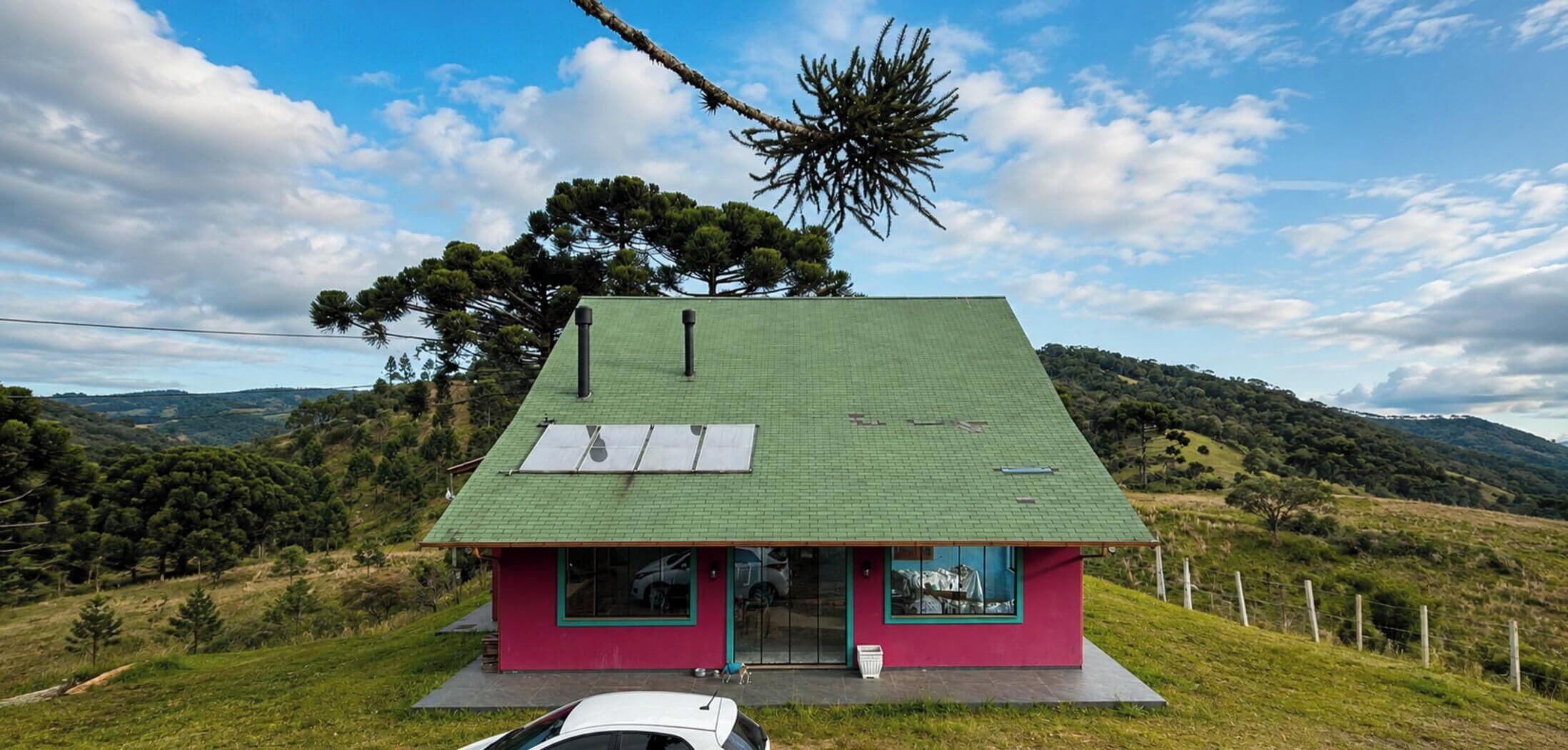 A single-story house with a green roof, a red facade, and a small porch area.