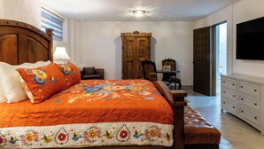 A bedroom with a large bed, a wooden wardrobe, a television, and a desk with chairs. - Cabo San Lucas Castle · Rooftop Sea Views (Cabo San Lucas)