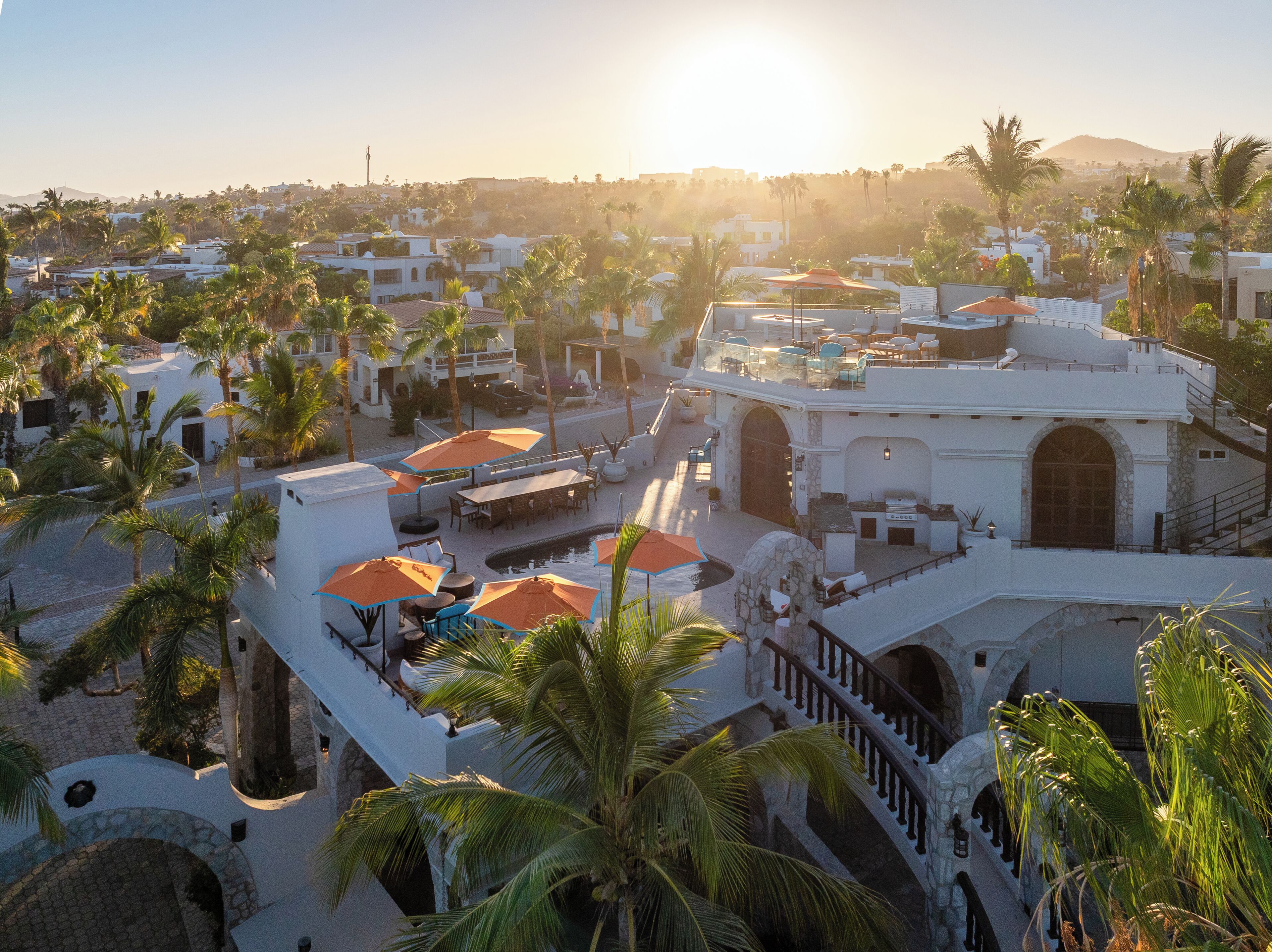 Un resort con varias construcciones, zonas de estar al aire libre y palmeras.