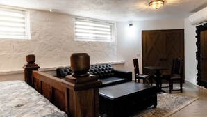 A bedroom with a bed, a wooden headboard, a black leather sofa, a small table, a chair, and a patterned rug. - Cabo San Lucas Castle · Rooftop Sea Views (Cabo San Lucas)