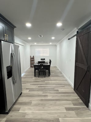 Eine Küche mit einem Edelstahl-Kühlschrank, einem Esstisch mit Stühlen und einer großen Schiebetür im Bauernhausstil.