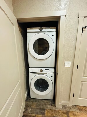 A laundry room with two stacked white Samsung washing machines. - The Modern + Cabin Retreat+ Grill (Stockton)