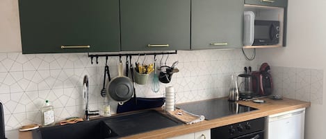 A kitchen with dark green cabinets, a microwave, a stove, and a sink.