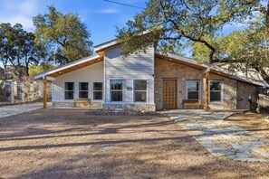 Une maison à deux étages, avec des fondations en pierre, un revêtement extérieur blanc et un toit en bois.