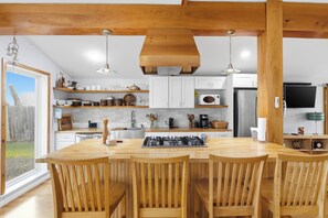 Une cuisine moderne avec des meubles en bois, un îlot central doté de sièges et une cuisinière intégrée.