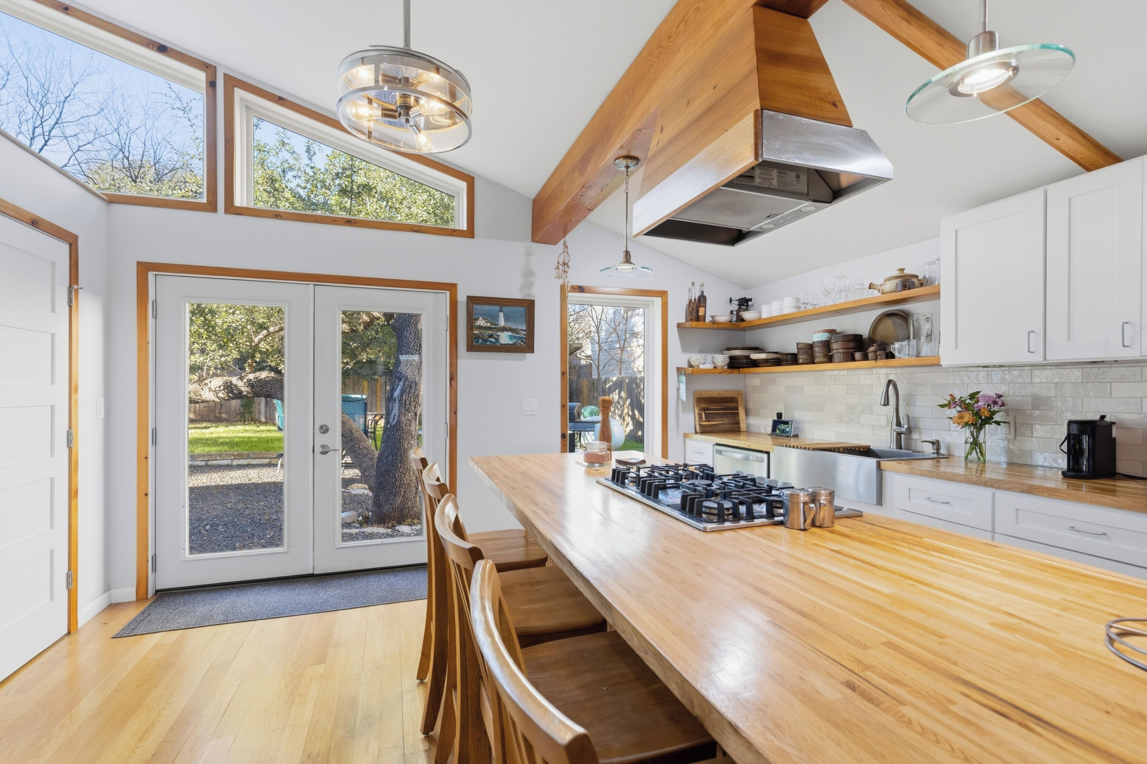 A modern kitchen with wooden countertops, a gas stove, and a dining area with a table and chairs.