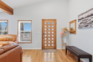 Ein Zimmer mit Holztür, einer Bank, einem gerahmten Bild und einem Fenster mit Jalousien.
