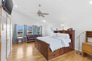 Une chambre spacieuse avec un grand lit, un ventilateur de plafond, un bureau et une vue sur l’extérieur.