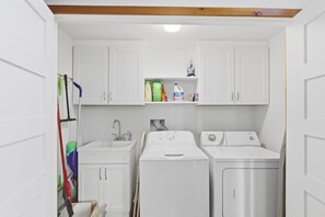 A compact laundry room with a sink, two washing machines, and storage cabinets. - Craftsman style lake cottage family & pet friendly (Austin)