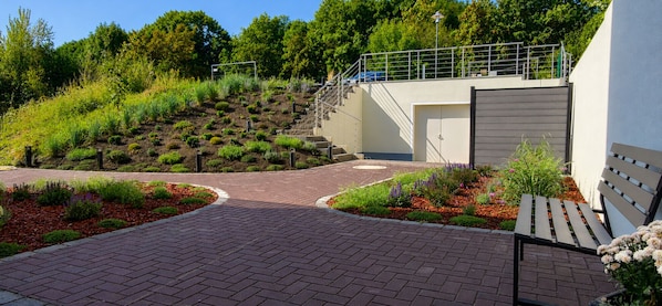 A paved entrance with a brick pathway leading to a building with a grey exterior and a metal staircase.