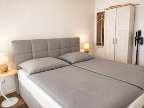 A bedroom with a bed, bedside tables, a wardrobe, and a lamp. - Spacious 60 m² vacation rental with 2 balconies, lake views, right on the water, and a boat dock (Neukieritzsch)