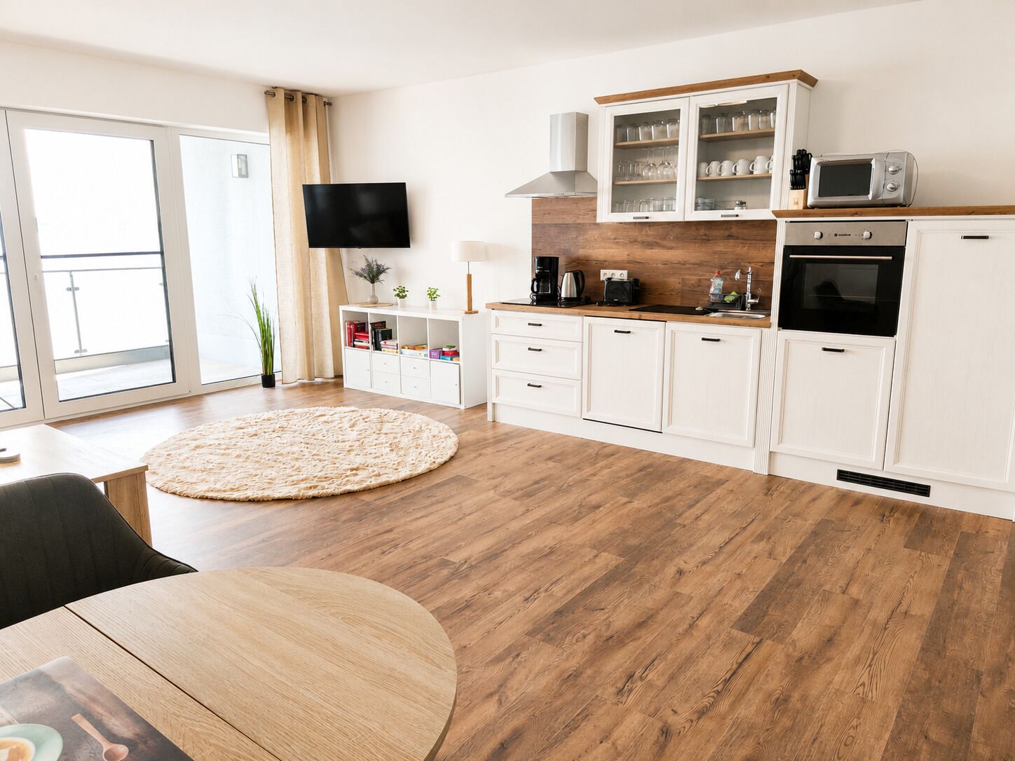 A modern kitchen with white cabinets, a wooden countertop, and a built-in oven.