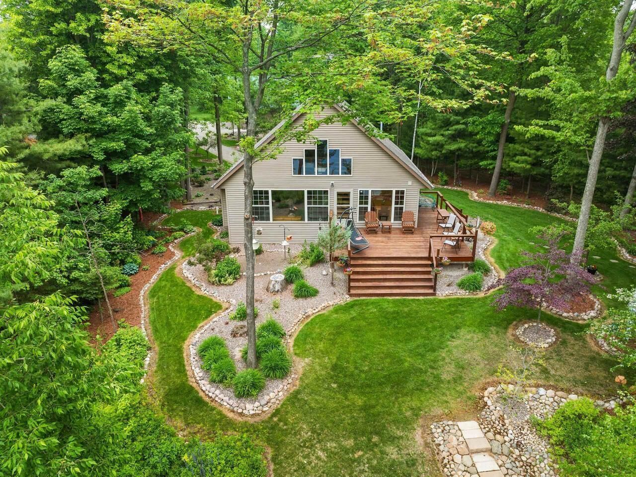Une maison à deux étages avec une terrasse et un jardin aménagé.