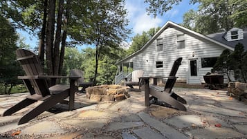 Une cabane dotée d’un patio en pierre, de chaises Adirondack et d’une terrasse en bois.