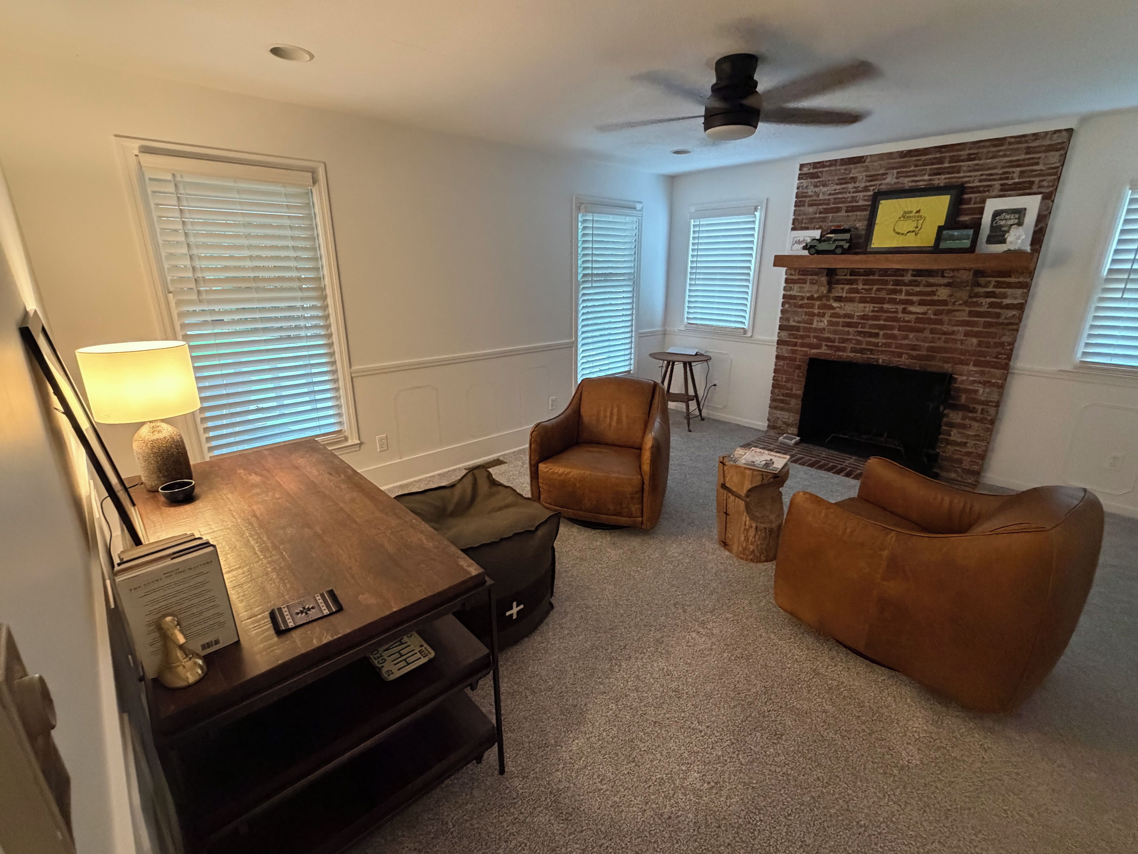 A living room with a fireplace, a ceiling fan, and a wooden coffee table.